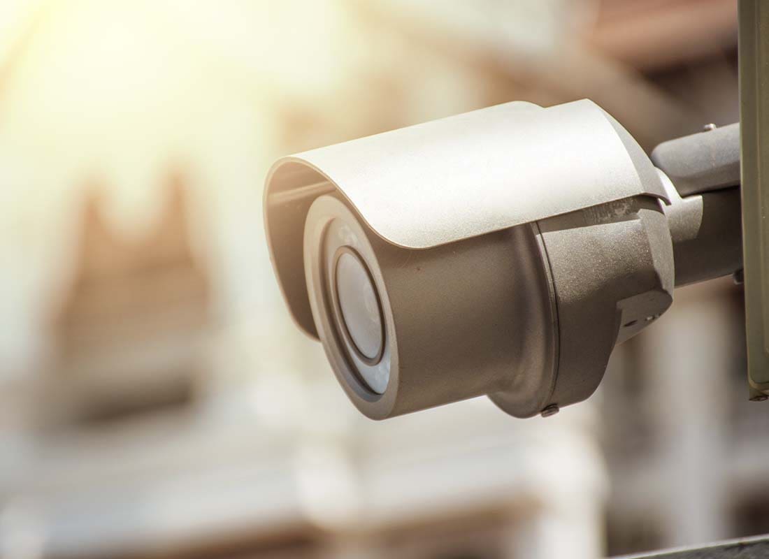 Alarm Contractor Insurance - Close-up of CCTV with View of Home in the Background and Heavily Blurred