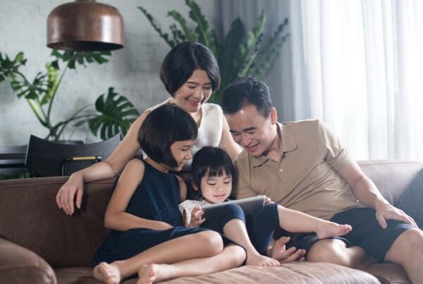 Umbrella Insurance - Happy Family Using a Tablet Together at on the Living Room Sofa of Their Modern Home